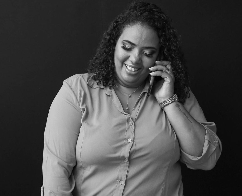 Lilian Coelho em retrato preto e branco, ao telefone, sorrindo